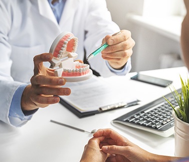 Dentist showing patient model of teeth