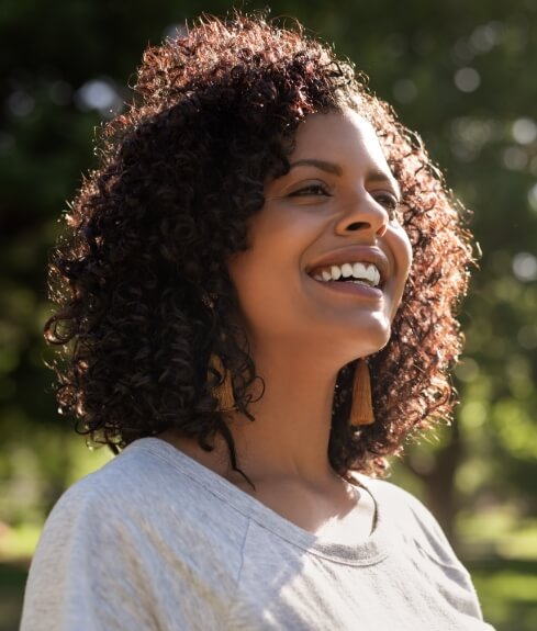 Woman smiling outdoors after gum disease treatment in Worcester