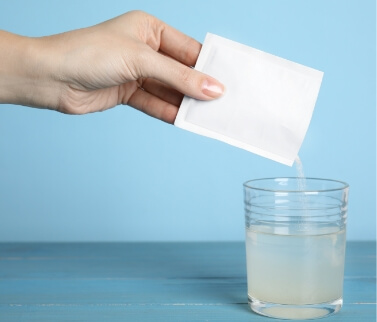 Hand dissolving powder into glass of water