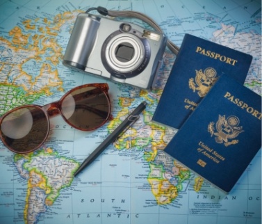 Two passports sunglasses camera and pen laying on world map