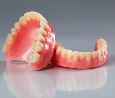 Set of full dentures resting on gray surface